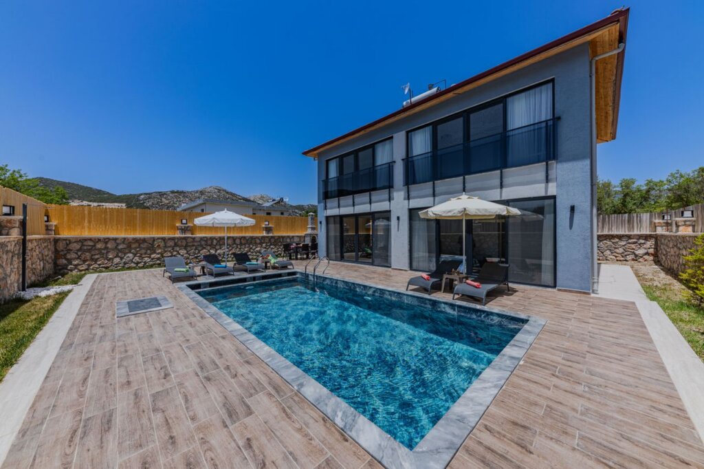 A contemporary villa with a swimming pool and patio area, perfect for summer vacations.