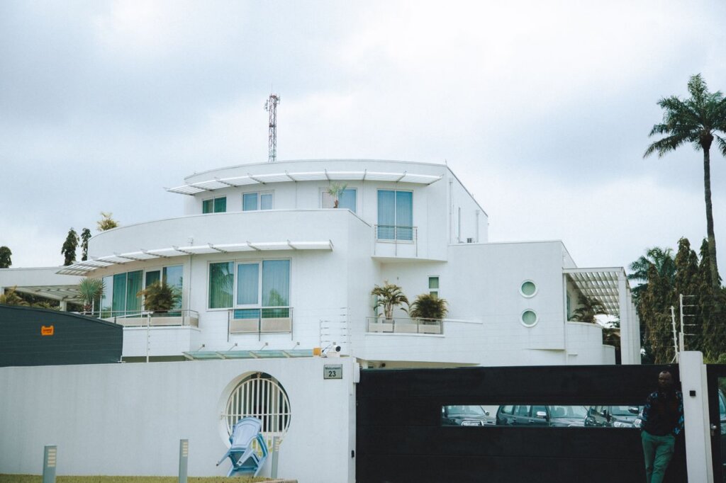 A contemporary white villa featuring lush green foliage under a cloudy sky day.
