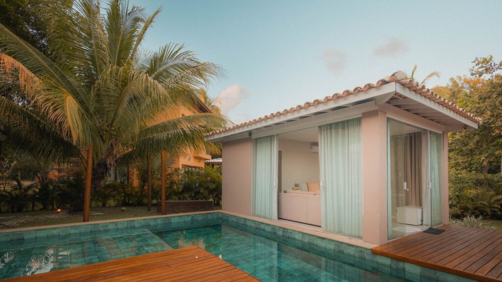 A serene tropical villa surrounded by palm trees and a pool at sunset, perfect for relaxation.